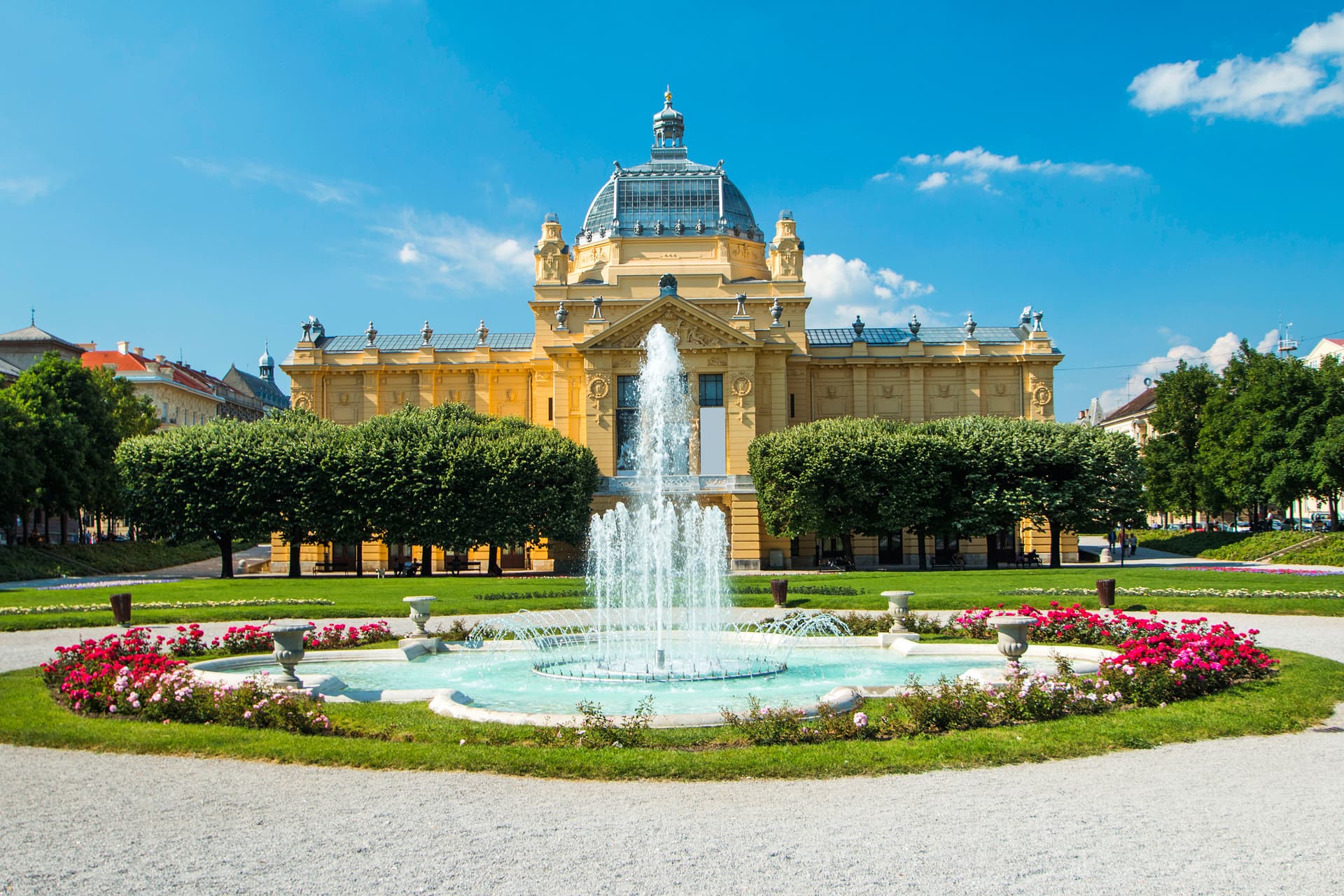 Art pavilion with a large fountain in a park with red roses in Zagreb.