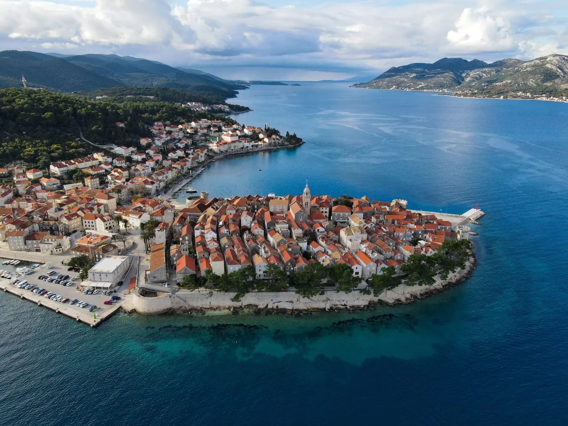 Korčula Old Town peninsula with terracotta roofs, clear blue sea, and Hvar Island in the distance.