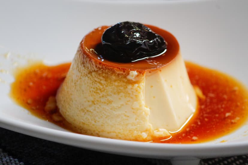 Rozata custard caramel dessert with caramel sauce and prune topping in a white bowl