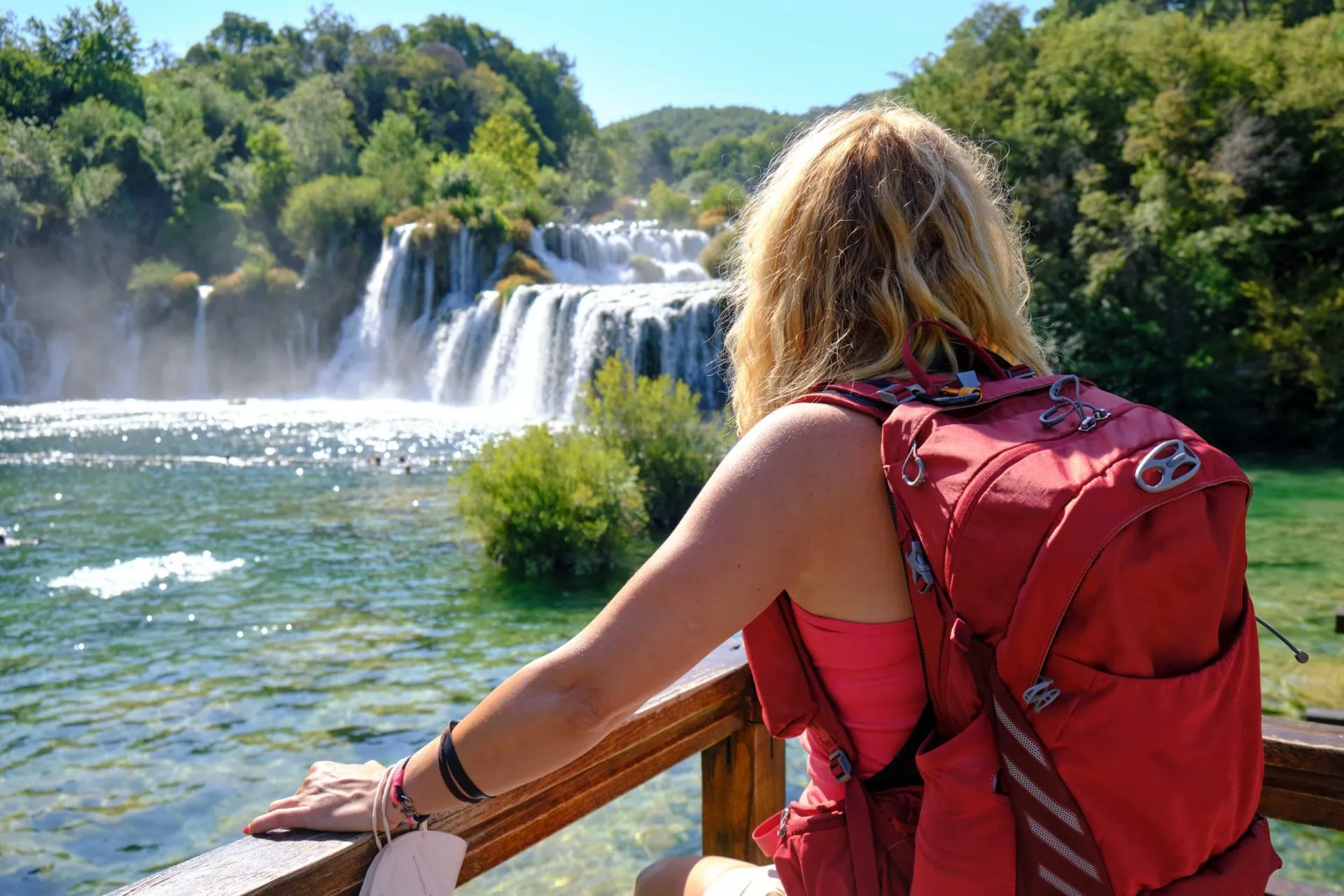 Woman tourist with backpack admires the Skradinski Buk waterfall in Krka National Park. Tourism, Croatia, Summer.